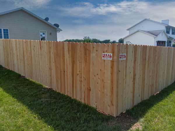 Dog eared style wood fence at the corner with Ideal Fence metal plaque place on both corners