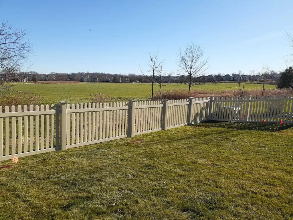 Beige vinyl picket fence facing the country side