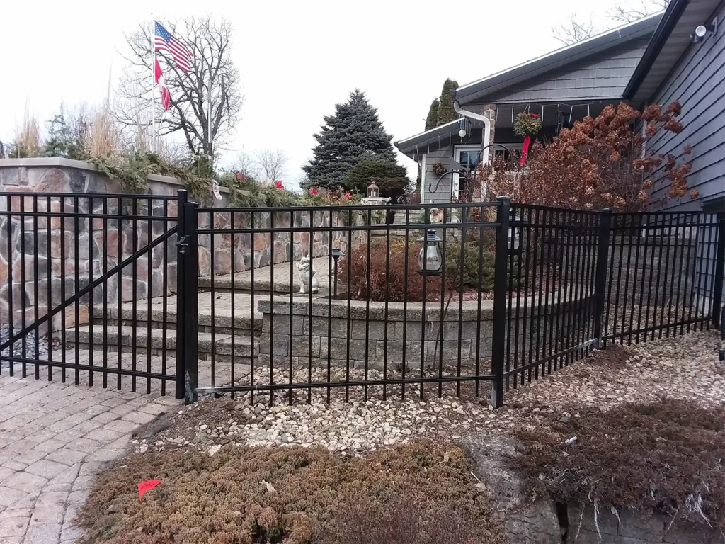 Black ornamental steel fence on the corner with large landscaping rocks