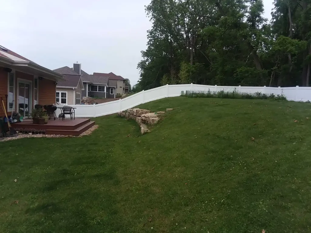Decorative white vinyl fence on a hillside next to a garden in the backyard