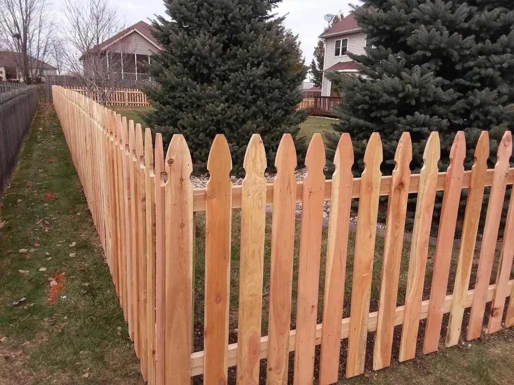 Corner of a wood pickt fence with evergreen trees