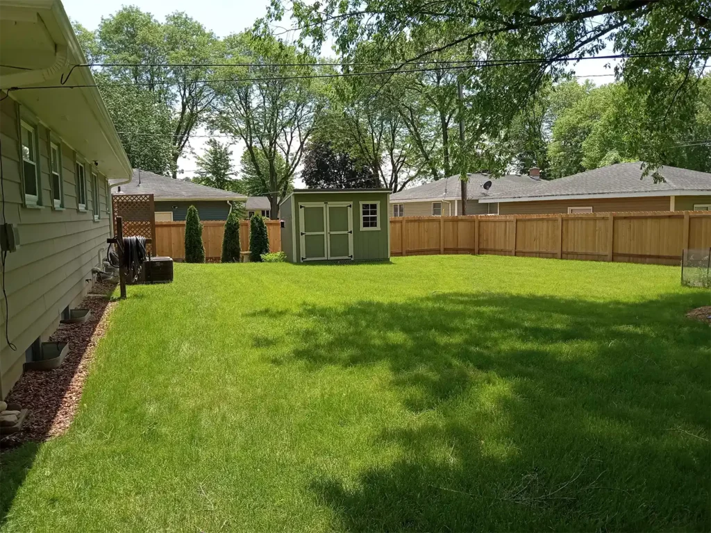 Tall 6' wood privacy fence in a backyard with a gray shed